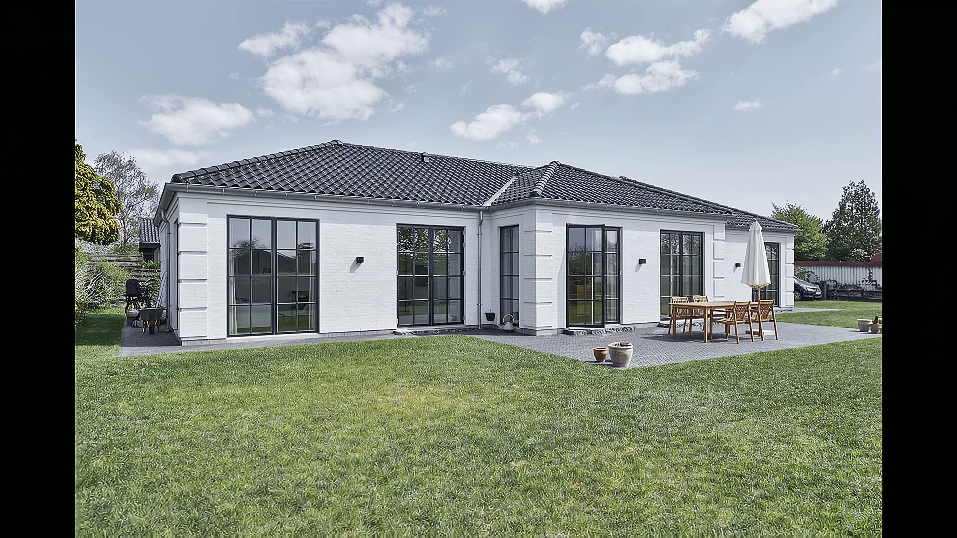 White brick Nordic home with dark tiled roof and black-framed windows